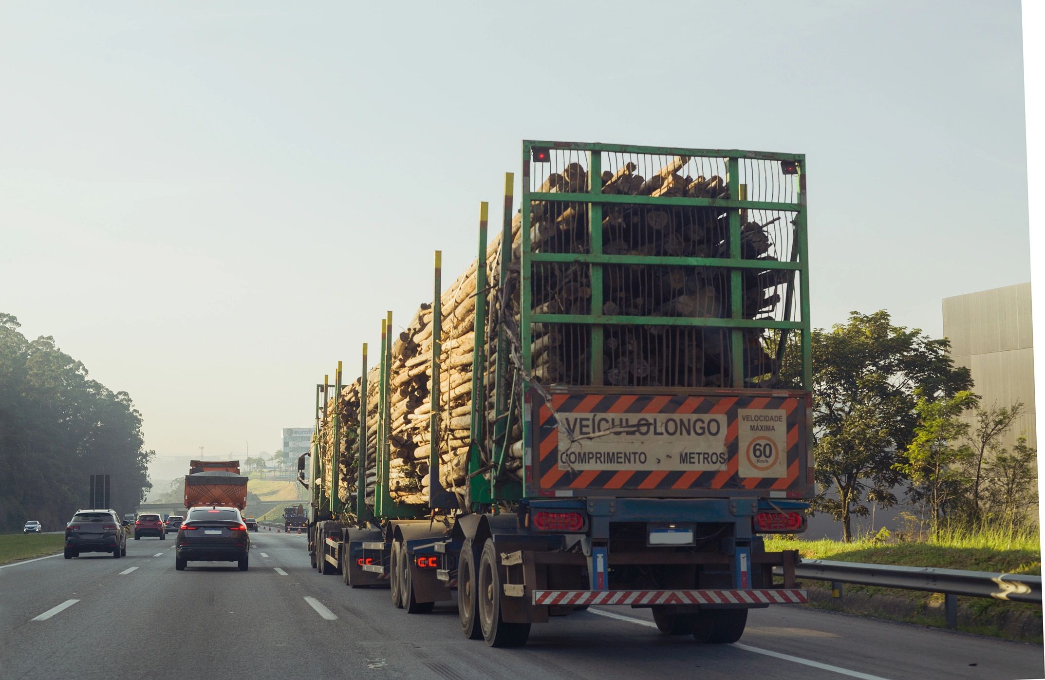 Open deck transport truck hauling a loaded trailer on the highway